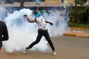 boy hurling back tear gas cannister